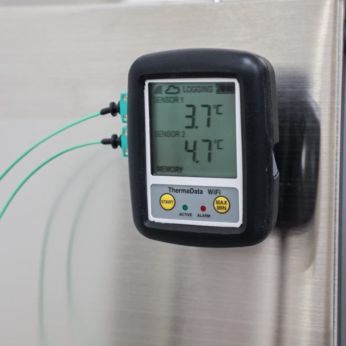 Un thermomètre numérique Thermomètre.fr à double affichage de la température, affichant 3,7°C et 4,7°C, fixé sur une surface métallique, équipé d'une connectivité Wi-Fi.